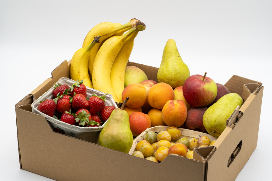 Saisonales Beispiel einer bunt gefüllten Firmenobstkiste mit Bananen und Beeren